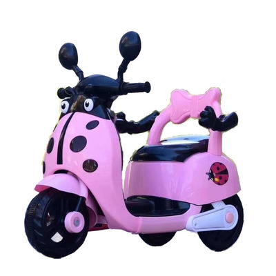 Des enfants montent sur une moto électrique en plastique avec des lumières et de la musique