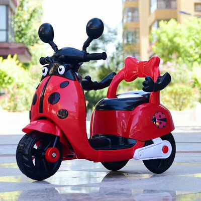 Des enfants montent sur une moto électrique en plastique avec des lumières et de la musique