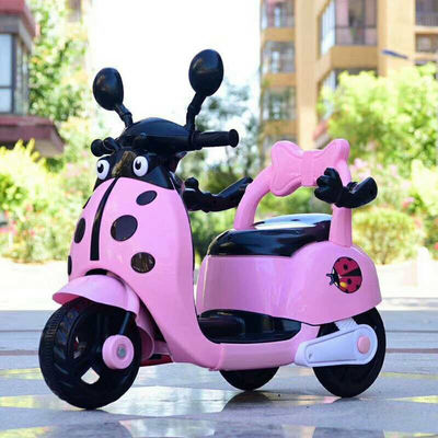 Des enfants montent sur une moto électrique en plastique avec des lumières et de la musique