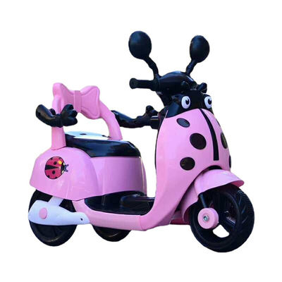 Des enfants montent sur une moto électrique en plastique avec des lumières et de la musique